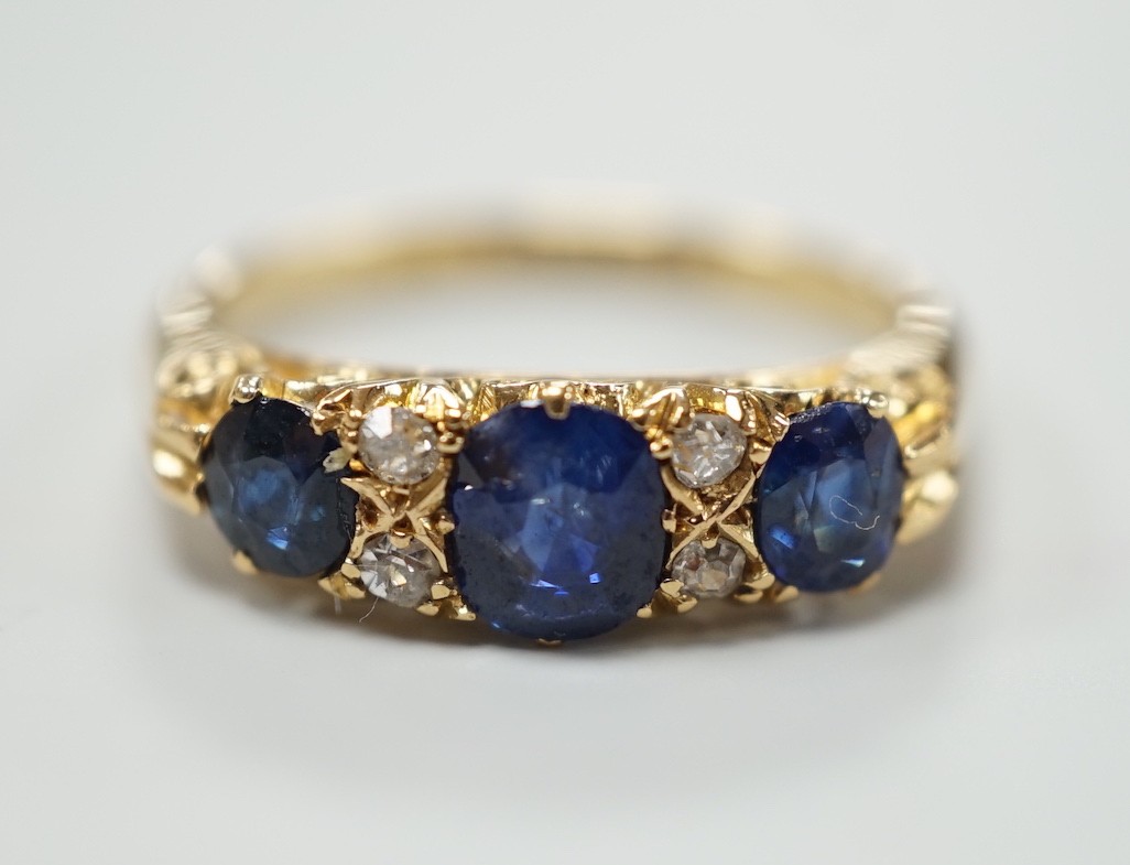 A George V 18ct gold and three stone sapphire set half hoop ring, with four diamond chip spacers, size M, gross weight 4.4 grams.